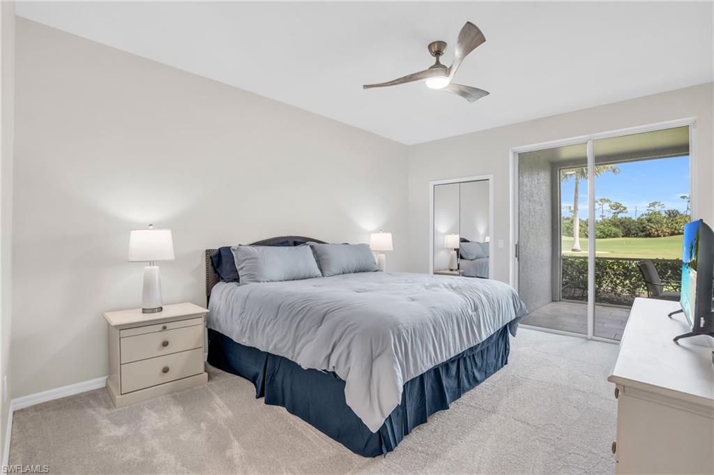 6025 Pinnacle Lane, Unit 602 Naples, FL 34110 - Photo 18 of 43 a spacious bedroom with a bed a table and large window with garden view