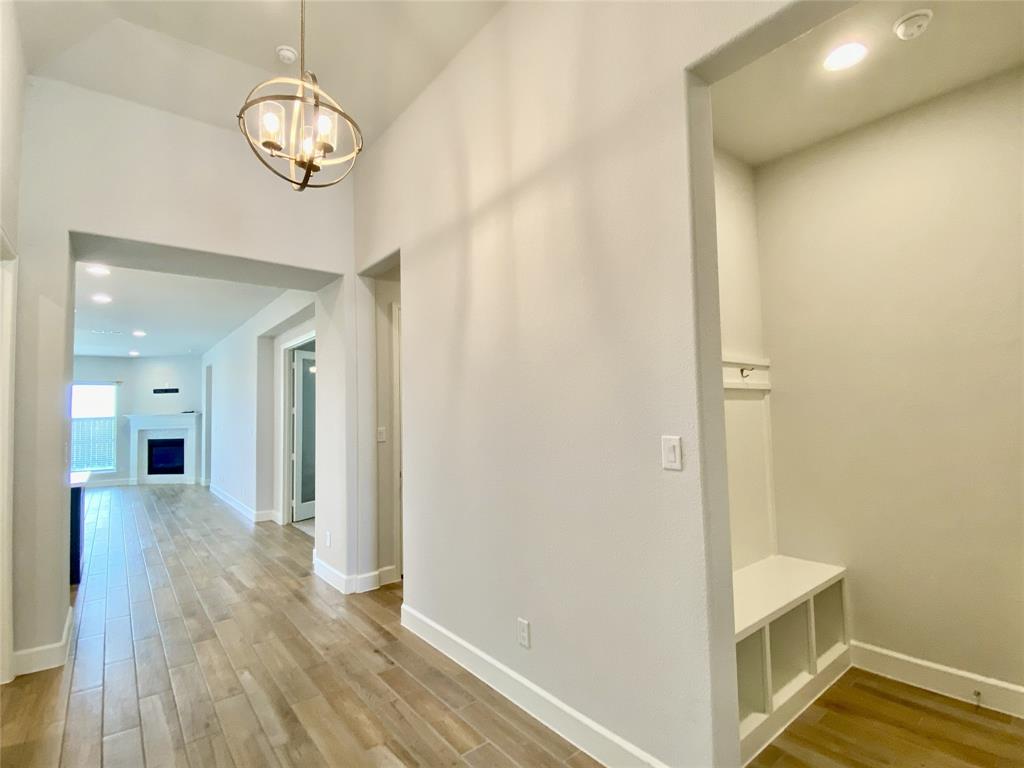 1937 Halkin Road Celina, TX 75009 - Photo 17 of 20 Open-concept hallway featuring wood-look tile flooring, a contemporary spherical chandelier, recessed lighting, and a bright, spacious layout that seamlessly connects the living areas.