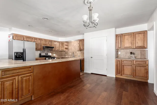 a view of a kitchen with kitchen island a counter top space a sink stainless steel appliances and cabinets