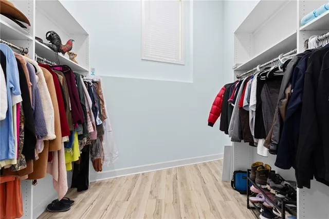 an empty room with wooden floor chandelier fan and windows