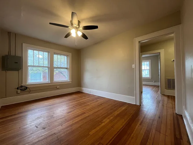 a view of empty room with wooden floor and fan