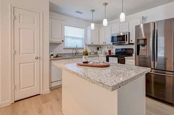 a kitchen with stainless steel appliances granite countertop a sink a stove a refrigerator a center island with wooden floor and cabinets