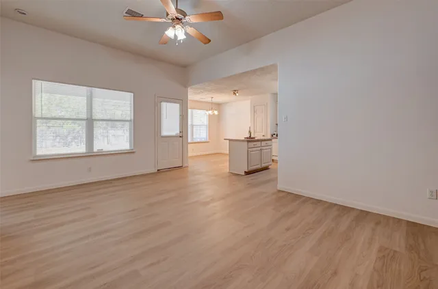 a view of an empty room with a window and wooden floor