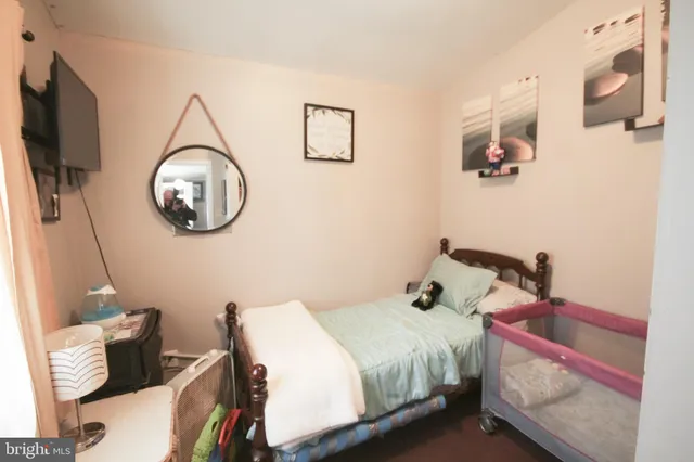 a bedroom with a bed a flat screen tv and a wall painting