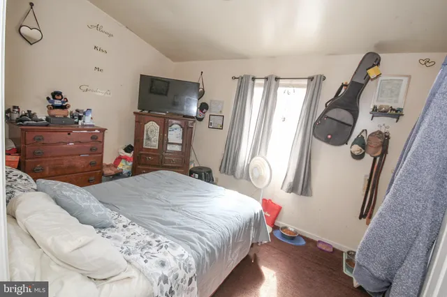 a bedroom with a bed a flat screen tv and a dresser