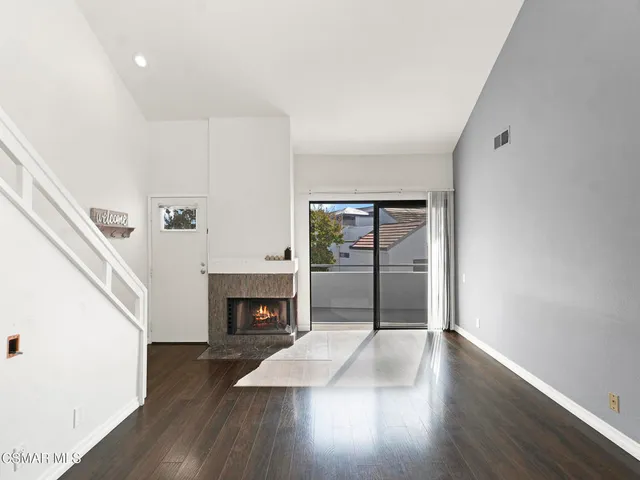 a big room with wooden floor fireplace and windows