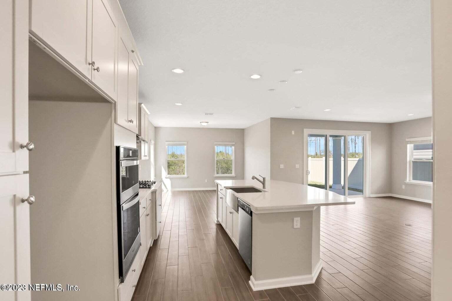 65 Torres Trace Street St. Augustine, FL 32095 - Photo 6 of 32 a kitchen with stainless steel appliances granite countertop a refrigerator a sink dishwasher a stove and white countertops with wooden floor