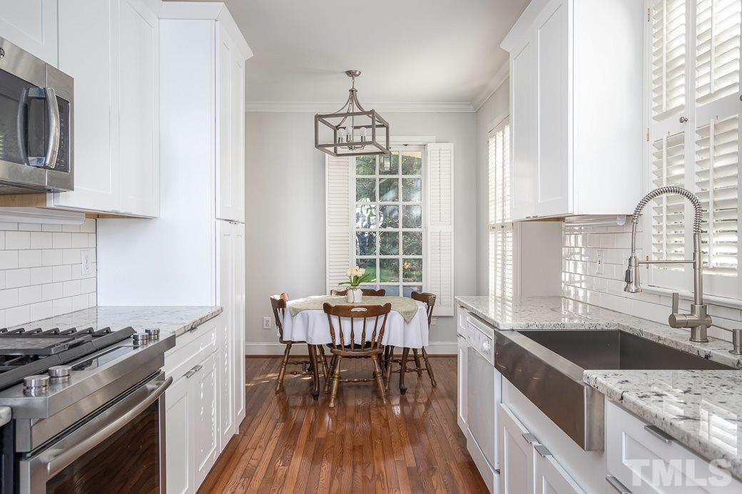 1305 Canfield Court Raleigh, NC 27608 - Photo 6 of 30 a kitchen with a stove a sink and wooden cabinets