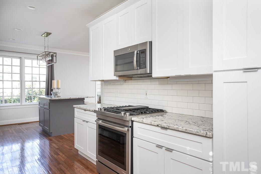 1305 Canfield Court Raleigh, NC 27608 - Photo 7 of 30 a kitchen with granite countertop cabinets stainless steel appliances and a wooden floor