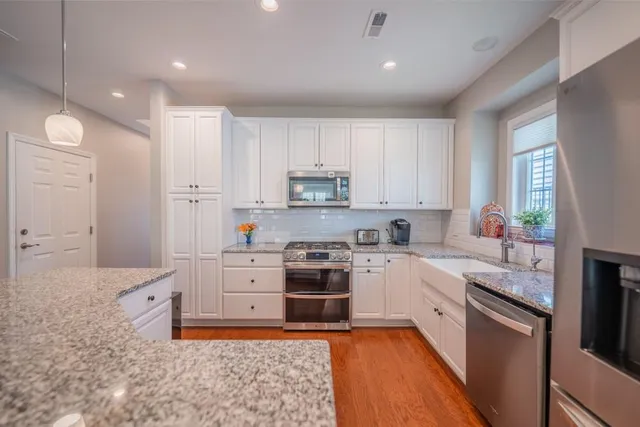 a large kitchen with stainless steel appliances granite countertop a stove a sink and a refrigerator
