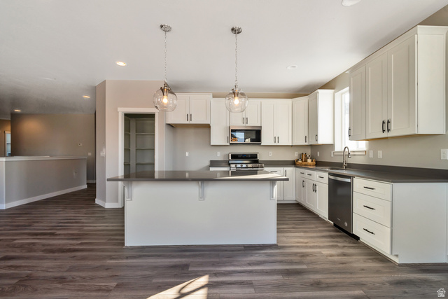 2449 Scarlet Road, Unit 249 Eagle Mountain, UT 84005 - Photo 14 of 26 Kitchen featuring dark wood-finish flooring, white cabinetry, dark countertops, and a center island with pendant lighting