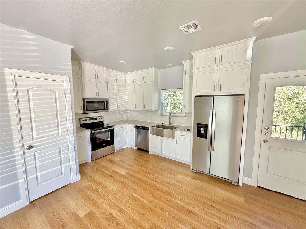 986 South 6th Avenue, Unit 988 Denison, TX 75021 - Photo 3 of 15 a kitchen with white cabinets and stainless steel appliances