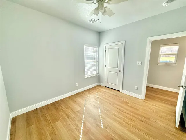 an empty room with wooden floor closet and windows