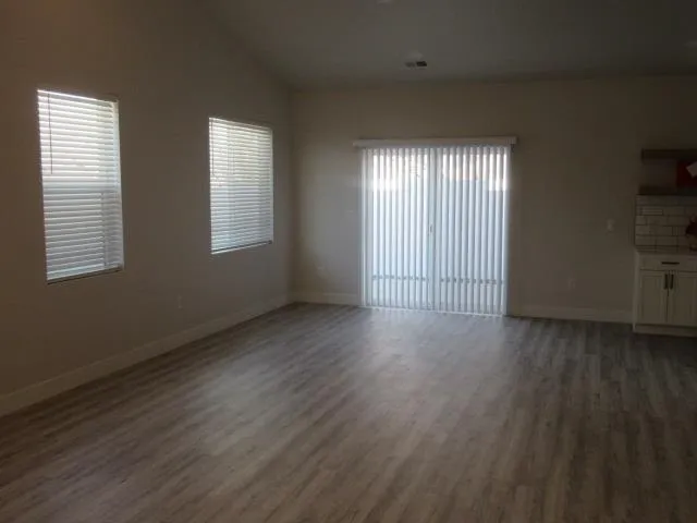 a view of an empty room with wooden floor and a window