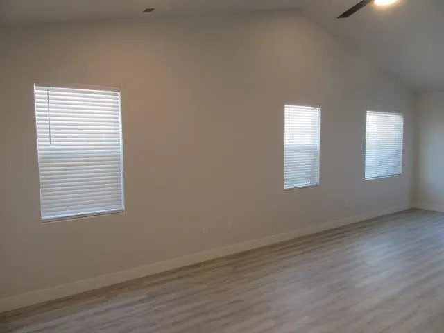 an empty room with wooden floor and windows