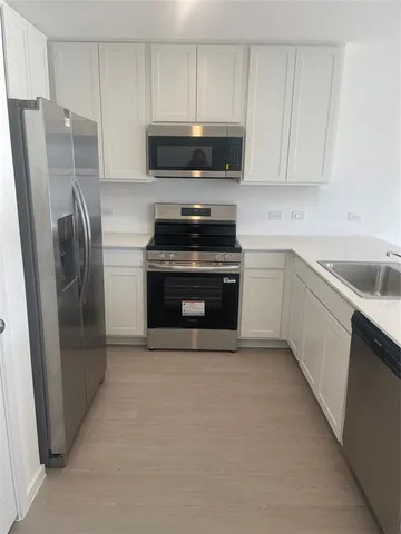 a kitchen with stainless steel appliances a refrigerator a sink a stove a microwave and cabinets