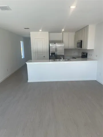 a view of kitchen with kitchen island microwave and cabinets