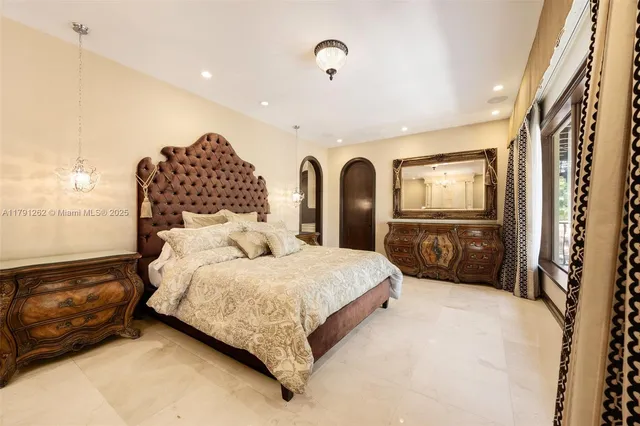 a bedroom with a bed large mirror on dresser and a chandelier