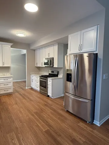 a kitchen with granite countertop a refrigerator and a stove top oven