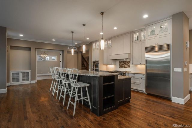 a kitchen with stainless steel appliances granite countertop a table chairs wooden floors and a sink