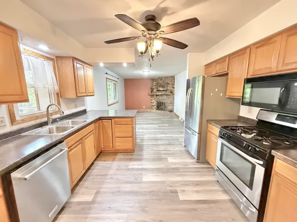 a large kitchen with stainless steel appliances granite countertop a stove top oven a sink dishwasher a dining table and chairs with wooden floor
