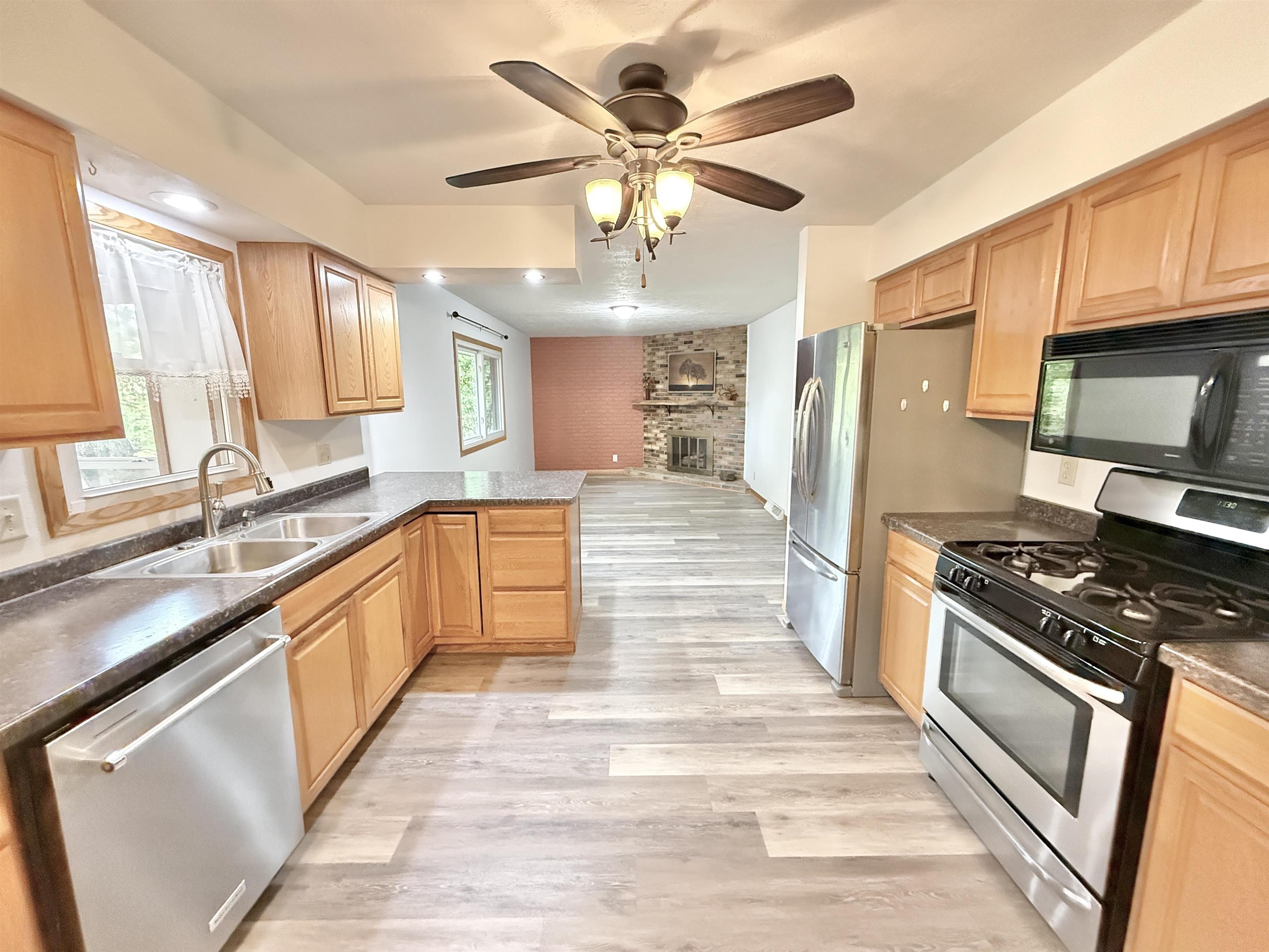 10620 Grover Oaks Road Roscoe, IL 61073 - Photo 1 of 32 a large kitchen with stainless steel appliances granite countertop a stove top oven a sink dishwasher a dining table and chairs with wooden floor