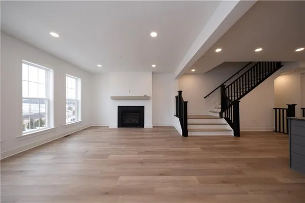 a view of an empty room with wooden floor and a fireplace