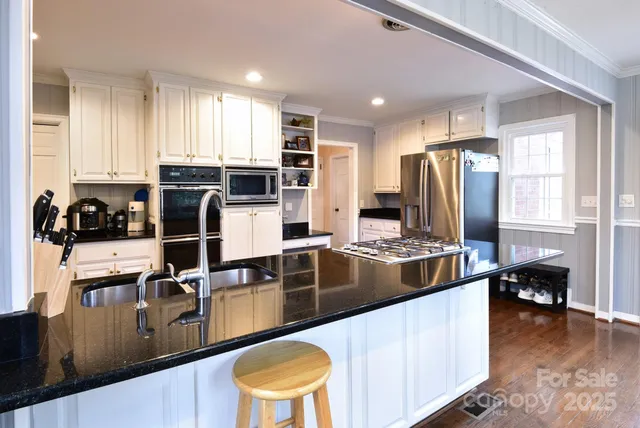 a kitchen with stainless steel appliances a refrigerator a stove a sink cabinets and a dining table