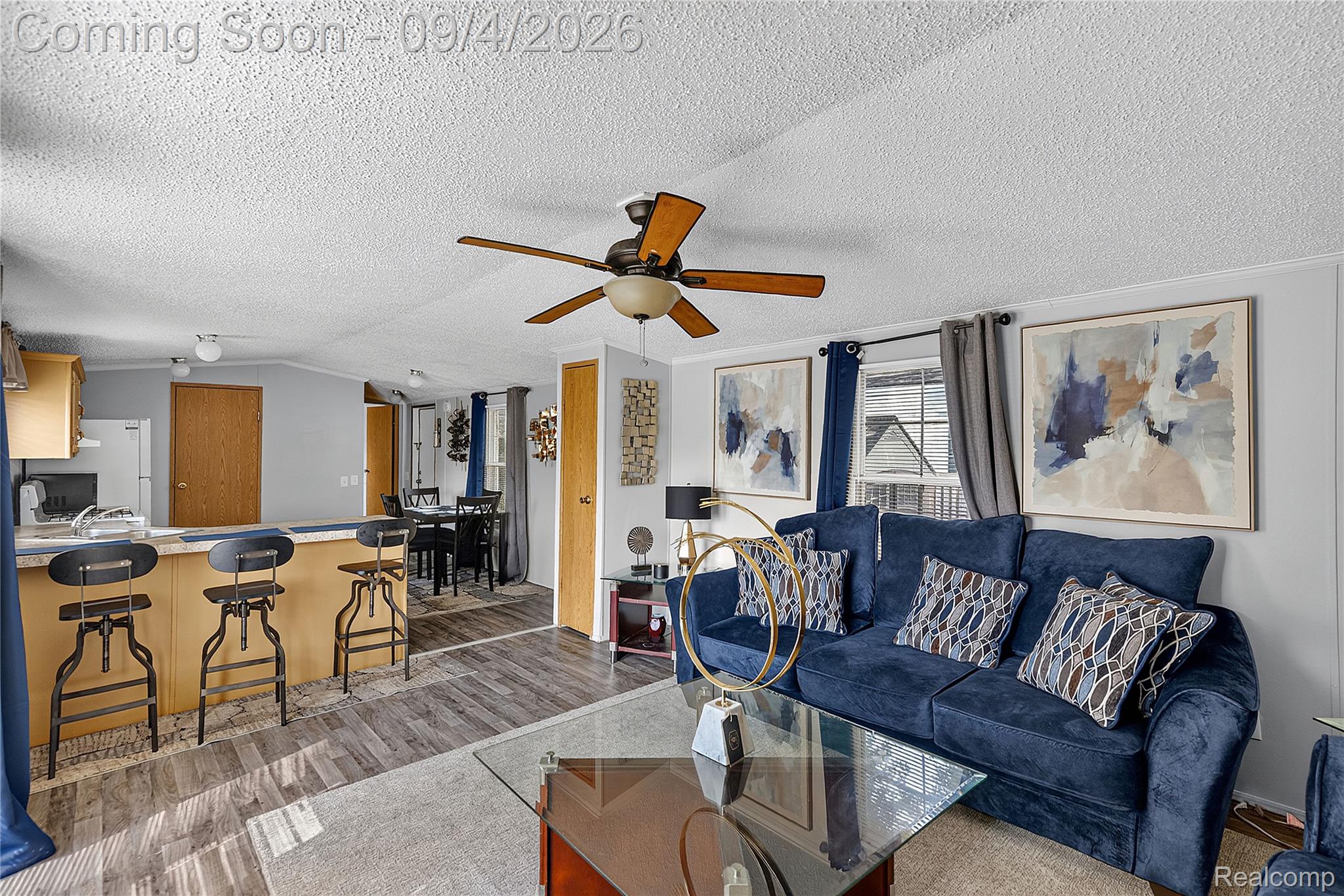 51074 Mott Road, Unit 200 Canton, MI 48188 - Photo 3 of 24 Wood-finish flooring, ceiling fan with integrated lighting, kitchen pass-through with bar seating, and light-toned walls
