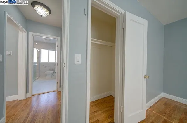 a view of a hallway with wooden floor and a bathroom