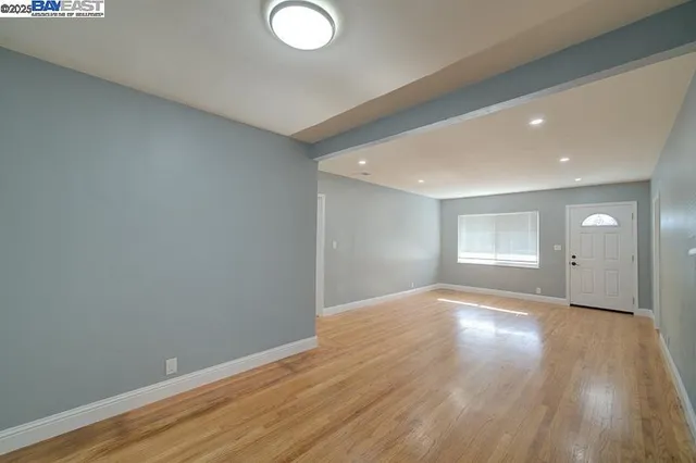 a view of an empty room with wooden floor and mirror