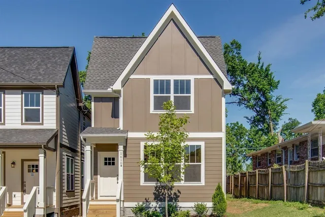 a view of a house with brick walls plants and large trees