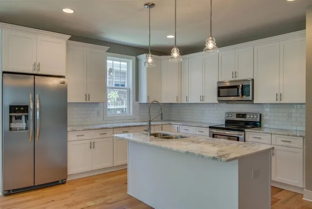a kitchen with granite countertop a refrigerator a sink and a stove