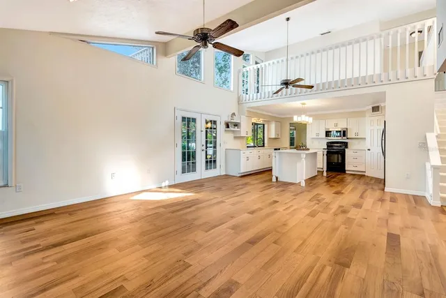 a view of empty room with wooden floor and fan