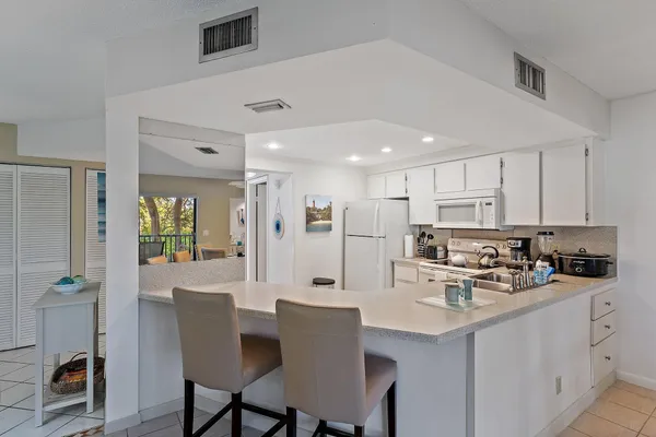 a kitchen with stainless steel appliances kitchen island granite countertop a dining table chairs and white cabinets