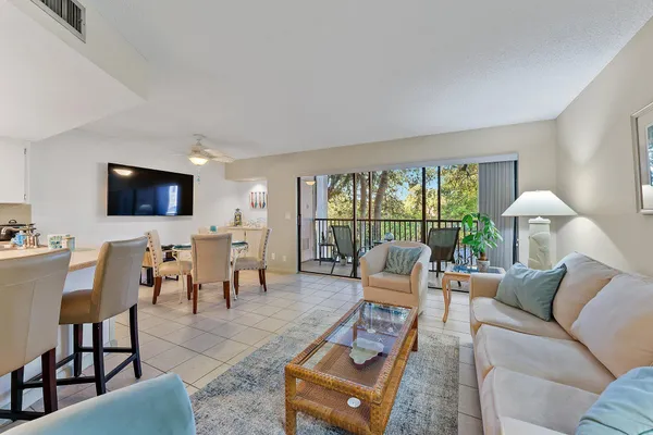 a living room with furniture a flat screen tv and a floor to ceiling window