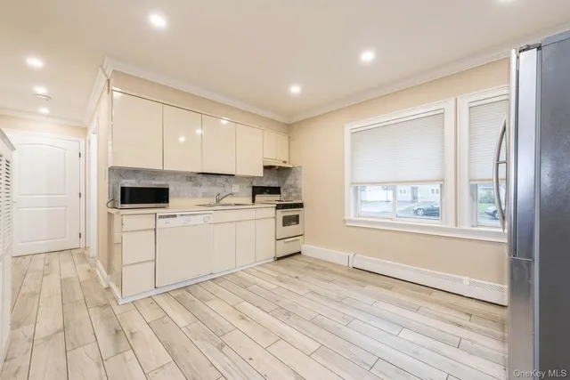 a kitchen with white cabinets and window