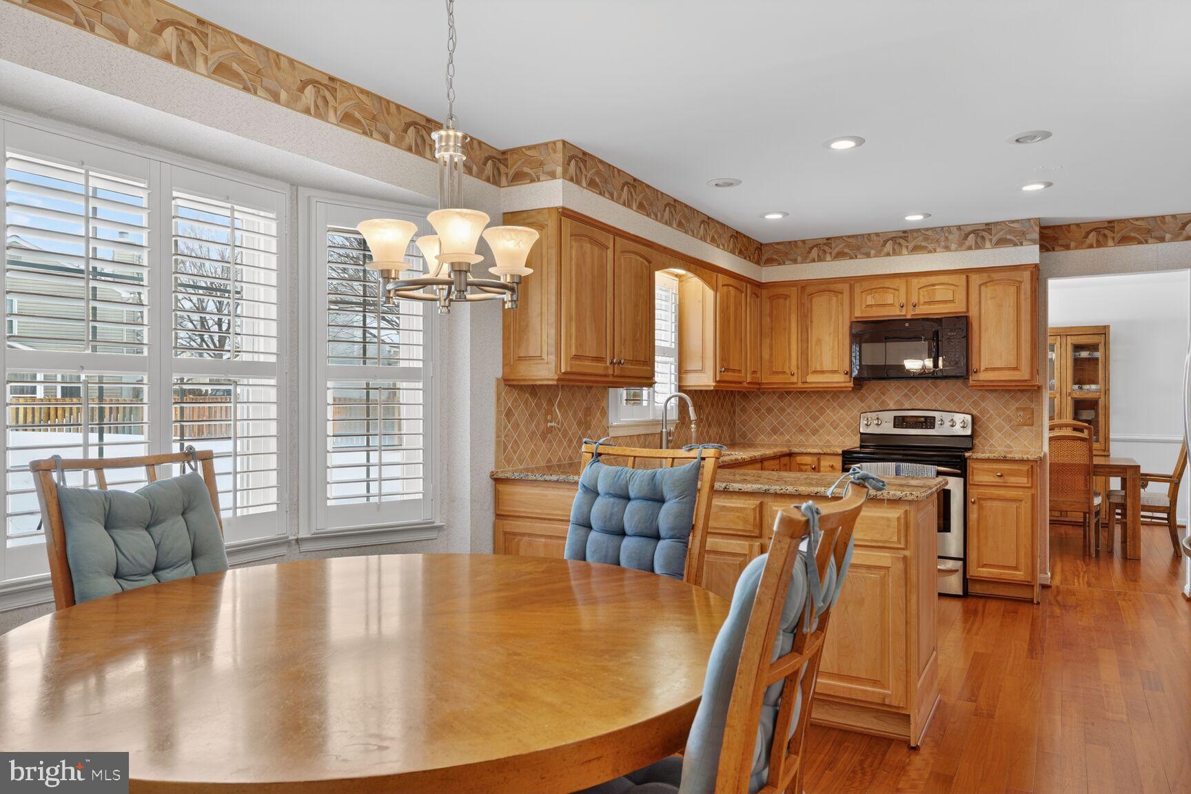 8836 Shadowlake Way Springfield, VA 22153 - Photo 38 of 77 a kitchen with stainless steel appliances granite countertop a stove top oven a refrigerator a dining table and chairs with wooden floor