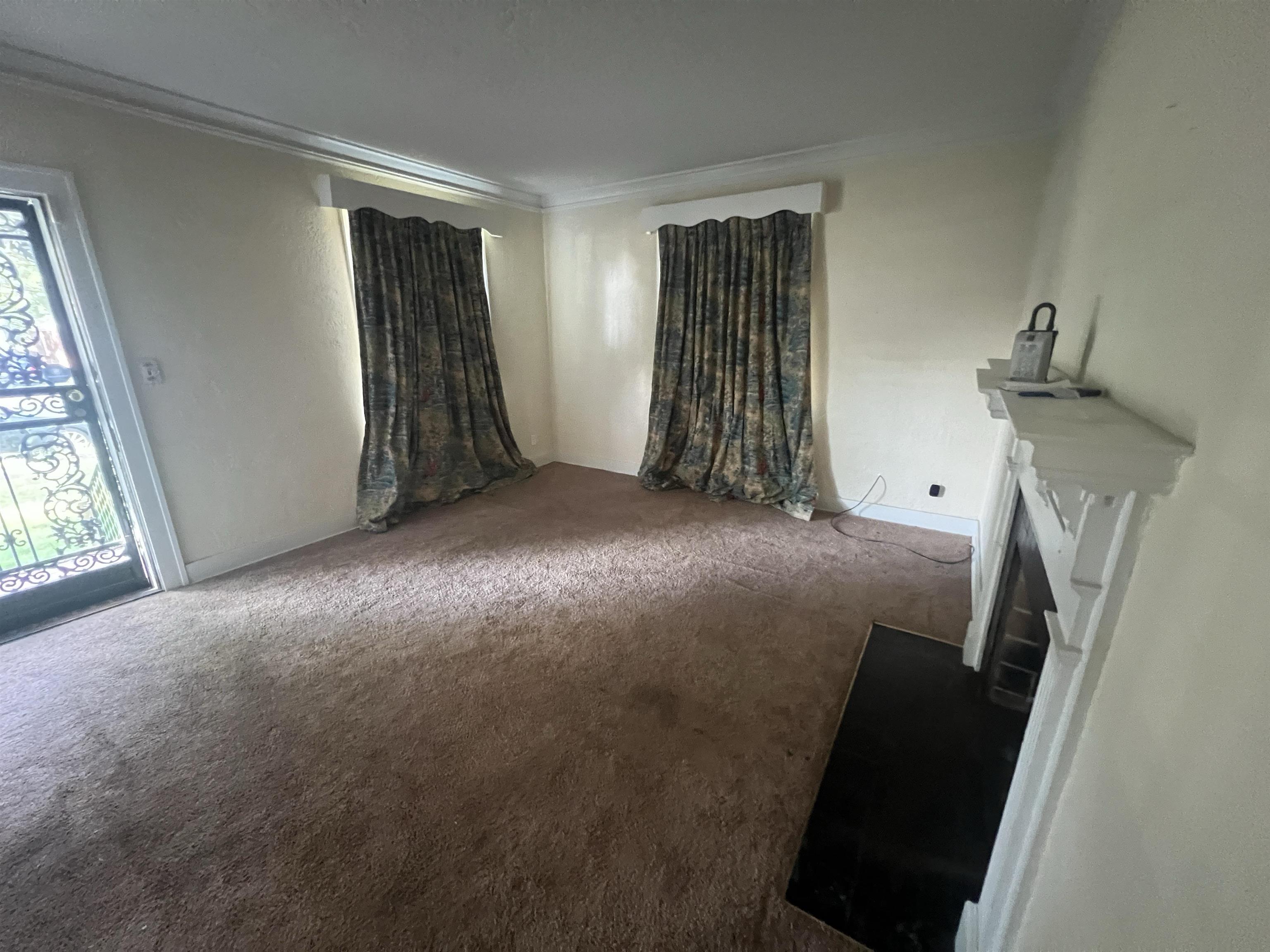 632 Spring Street Memphis, TN 38112 - Photo 8 of 37 Unfurnished living room featuring carpet floors, crown molding, and a fireplace