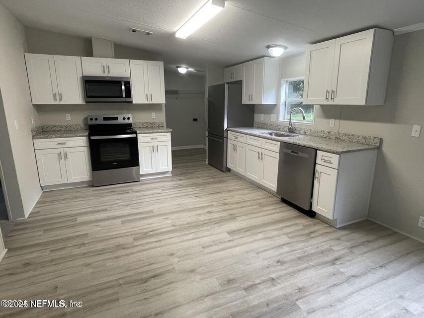 67089 Elnora Lane Yulee, FL 32097 - Photo 8 of 19 a kitchen with granite countertop a stove top oven a sink and white cabinets