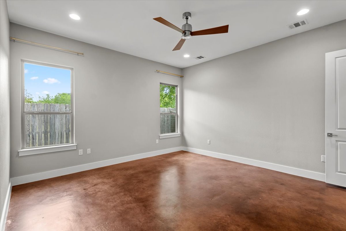 913 Stobaugh Street, Unit B Austin, TX 78757 - Photo 24 of 40 A well-lit primary bedroom featuring rich brown concrete flooring and ample natural light through multiple windows.