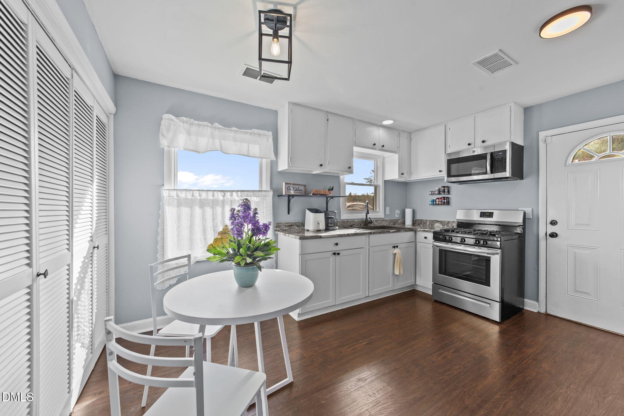 2874 Beulahtown Road Kenly, NC 27542 - Photo 12 of 40 a kitchen with stainless steel appliances kitchen island granite countertop a stove a sink dishwasher a microwave oven and a dining table with wooden floor