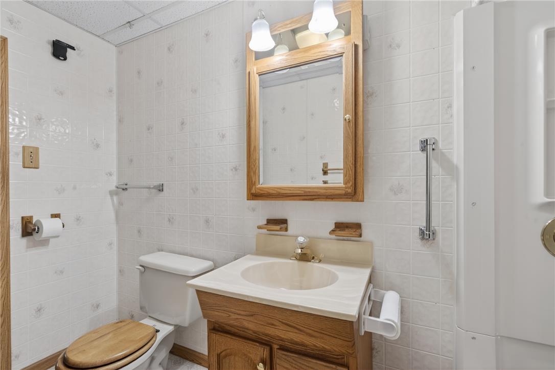 18 White Oak Road Nesquehoning, PA 18240 - Photo 29 of 52 A well-appointed bathroom with tile walls features a vanity, toilet, and mirrored medicine cabinet.