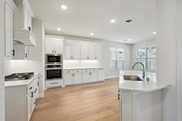 a kitchen with stainless steel appliances a sink a stove a refrigerator cabinets and a window