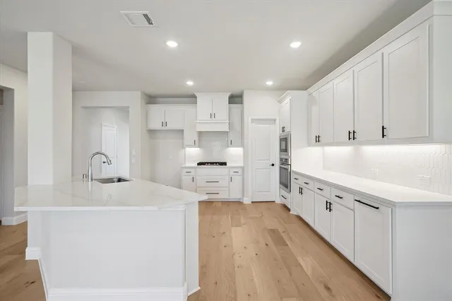 a large white kitchen with white cabinets and stainless steel appliances