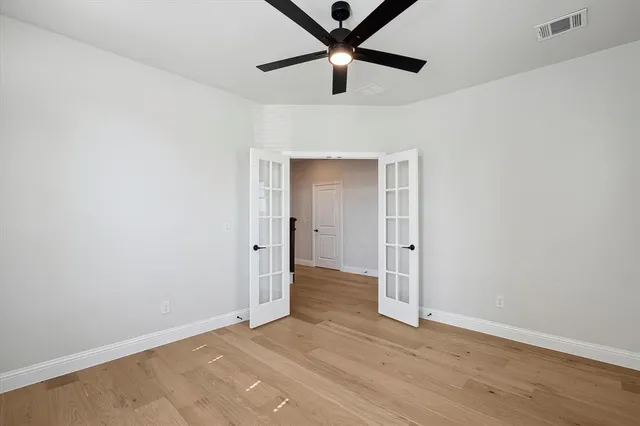 an empty room with wooden floor and ceiling fan
