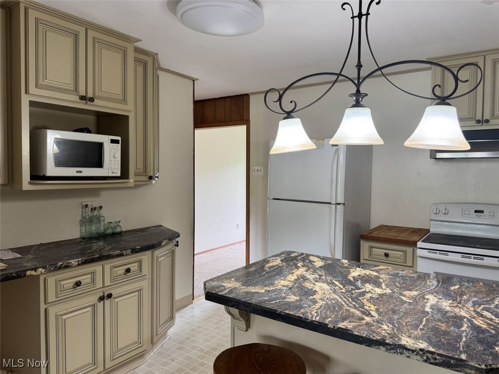 16510 Mock Road Berlin Center, OH 44401 - Photo 13 of 29 Kitchen with white appliances, cream cabinets, under cabinet range hood, hanging light fixtures, and a kitchen breakfast bar