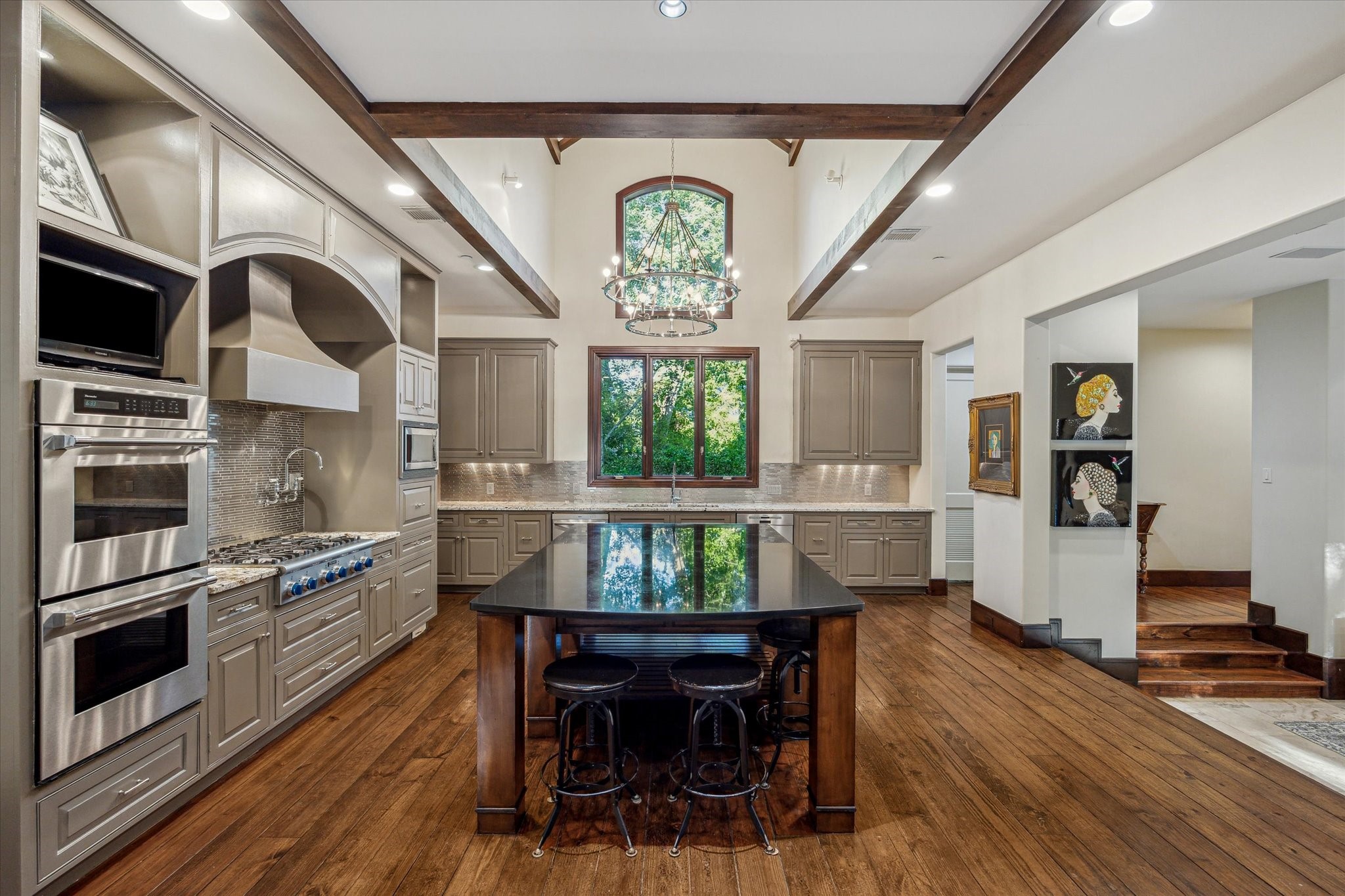 354 Piney Point Road Houston, TX 77024 - Photo 14 of 50 The main kitchen boasts vaulted ceilings with a transom window, creating a bright and open atmosphere. A beautifully centered island provides ample seating and storage, perfect for entertaining. The Thermador gas stove is complemented by a convenient prep sink nearby.