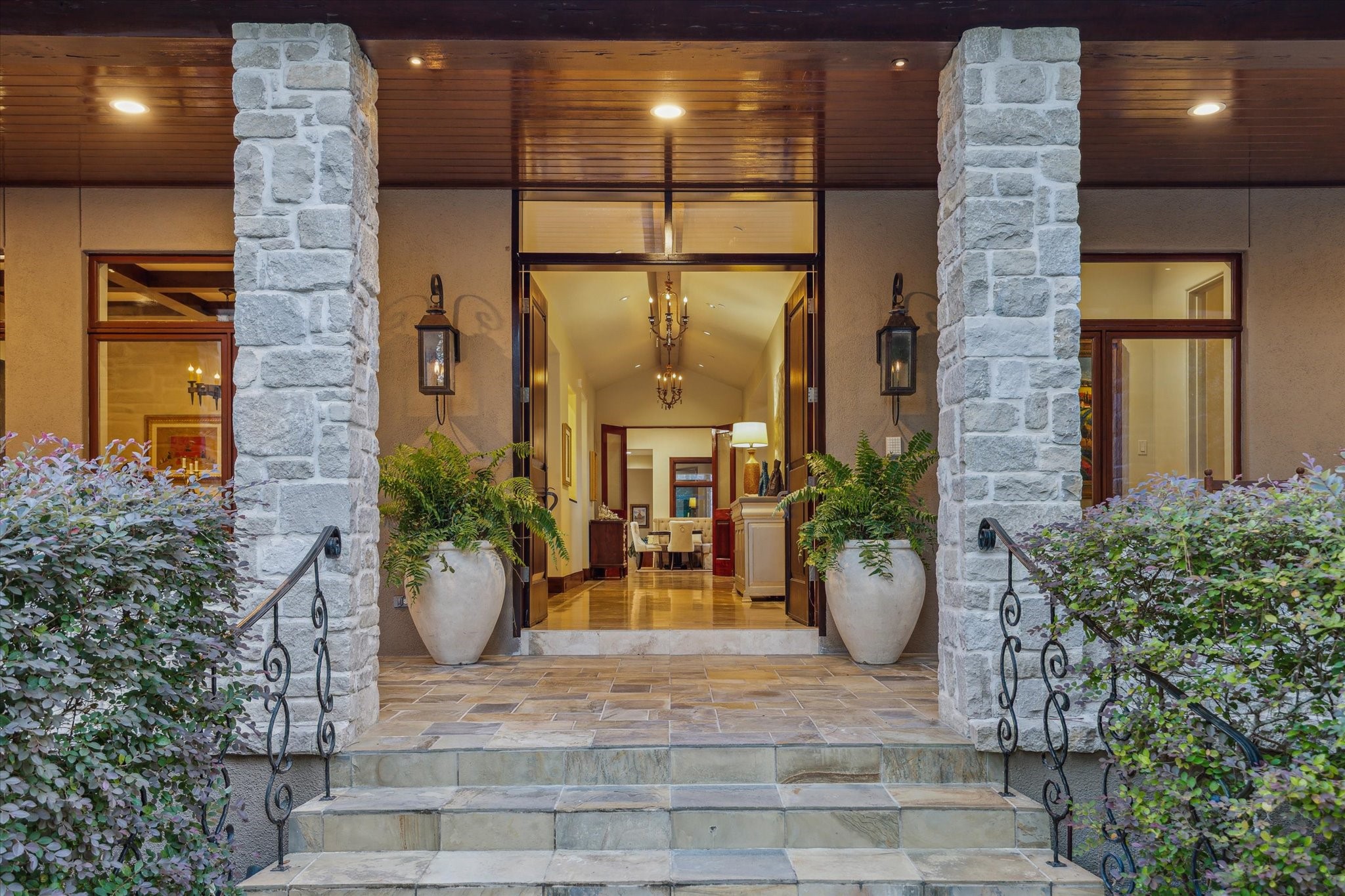 354 Piney Point Road Houston, TX 77024 - Photo 5 of 50 Wrought-iron railings and slate tile guide you to an expansive patio, illuminated by gas lanterns and recessed lighting throughout. Double wood doors, accompanied by transom windows, open into an elegant, symmetrical foyer.