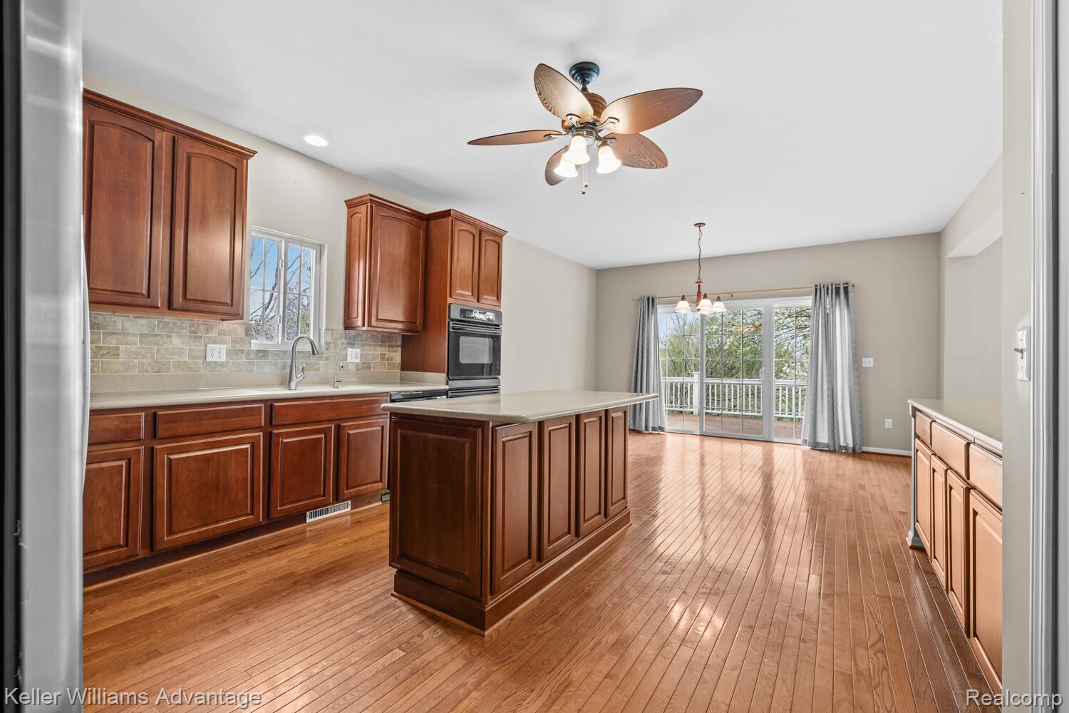 4100 Norwich Court Rochester, MI 48306 - Photo 14 of 72 Kitchen with ceiling fan, light wood finished floors, a center island, black oven, and decorative backsplash